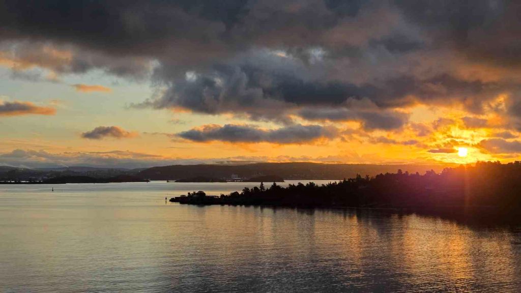 Hafeneinfahrt Oslofjord mit Kreuzfahrtschiff und Inselufern im Morgenlicht