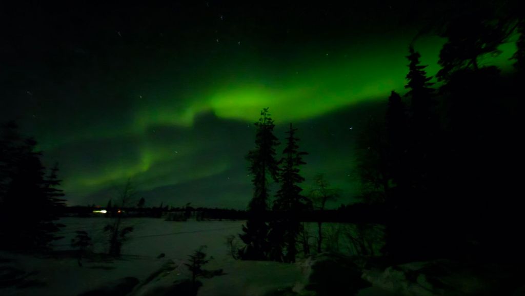 Nordlichter am Himmel über verschneiter Winterlandschaft in Finnland